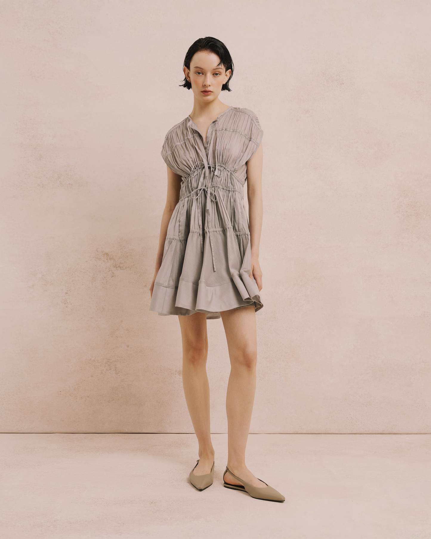 Model wears the Amelia Toro Cotton Voile Tiered Mini Dress in grey, front view