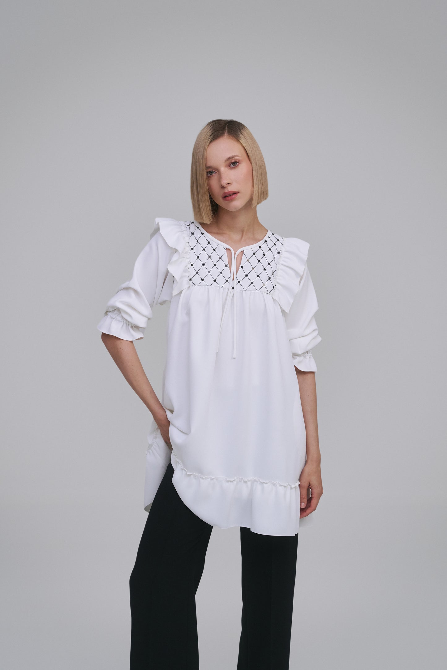 Model wears the Amelia Toro Embroidered Ruffled Short-Sleeve Mini Dress in White, front view