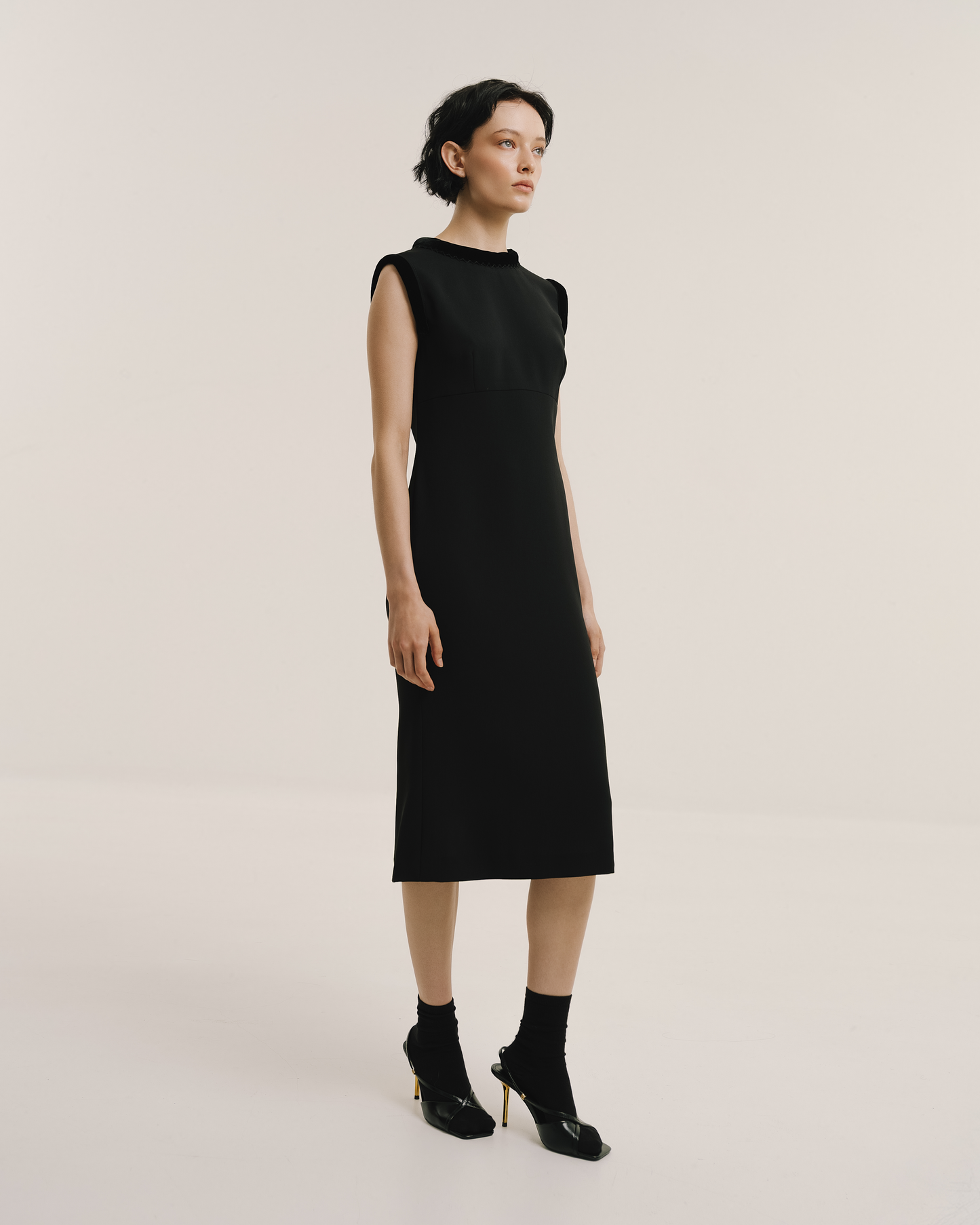 Model wears the Amelia Toro Velvet-Trimmed Black Midi Dress in black, front view