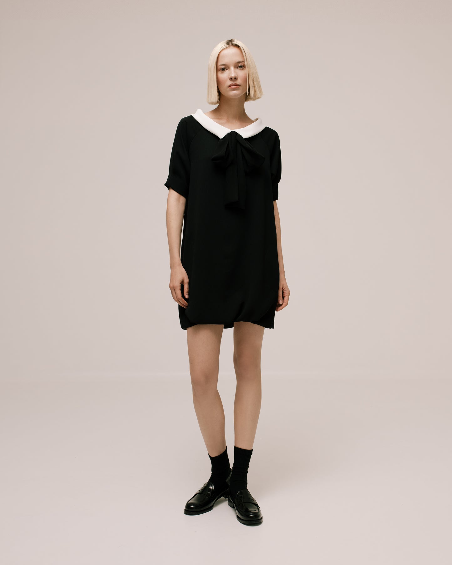 Model wears the Amelia Toro Bateau-Collar Bow-Tie Cady Mini Dress in Black, front view
