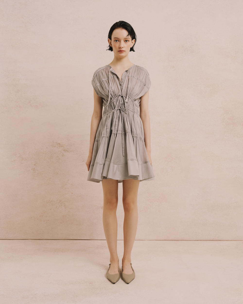 Model wears the Amelia Toro Cotton Voile Tiered Mini Dress in grey, front view