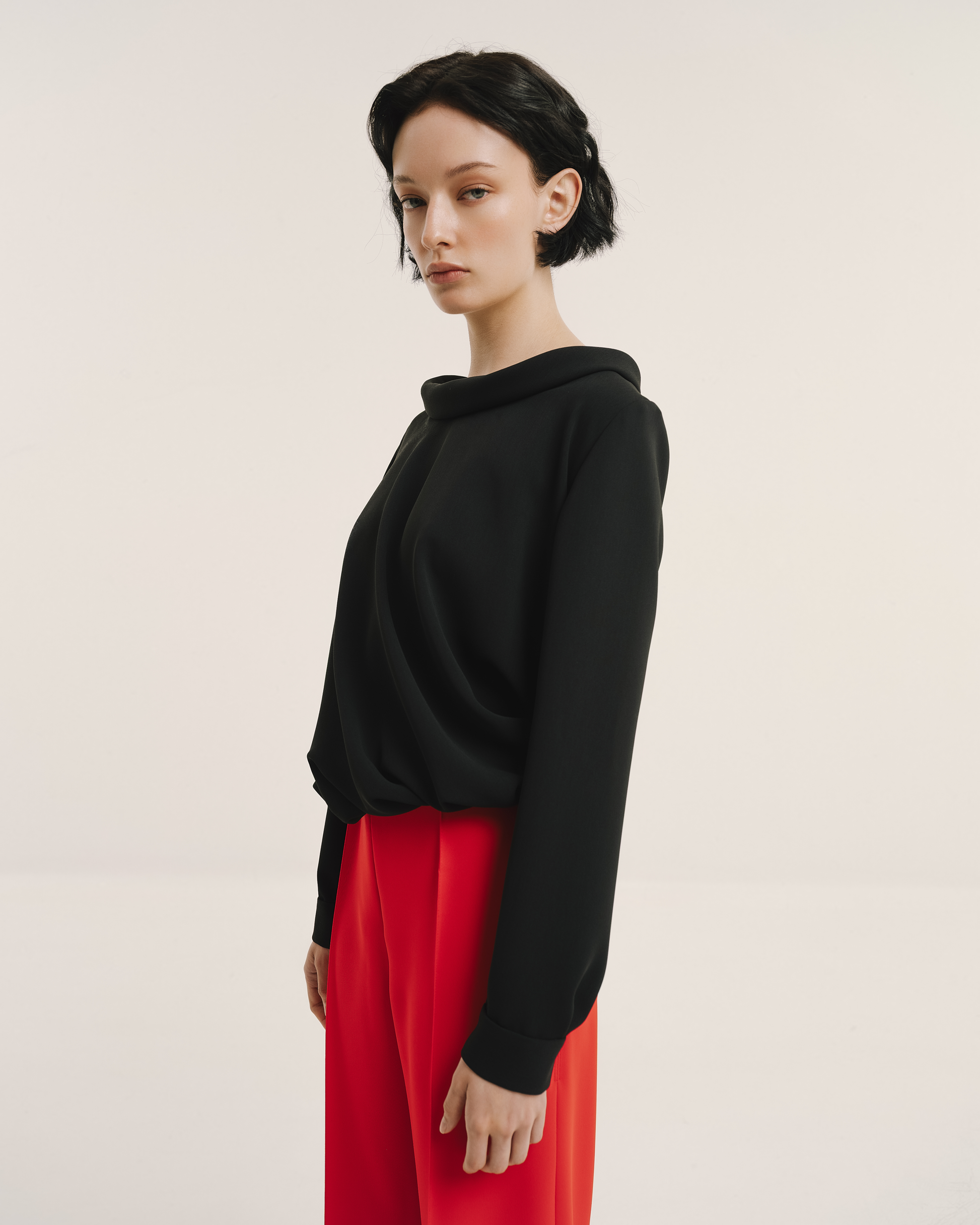 Model wears the Amelia Toro Draped-Waist Long-Sleeve Blouse in black, front view