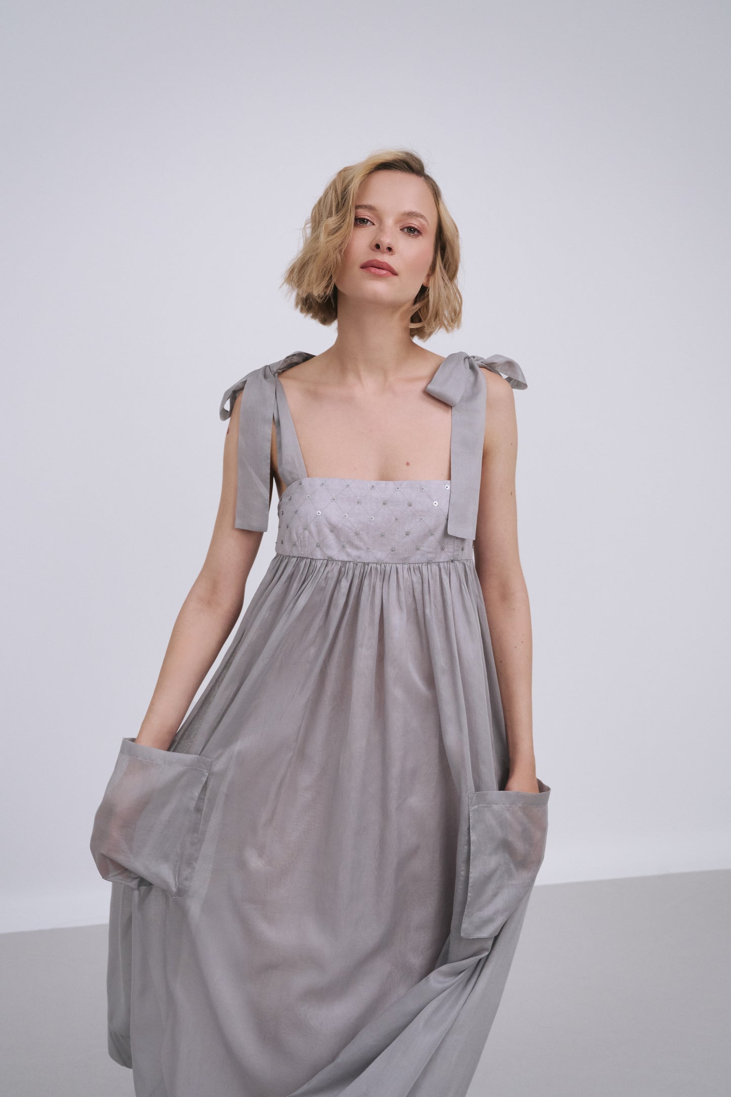 Model wears the Amelia Toro Embroidered Cotton Voile Midi Sundress in Grey/Pink, front view