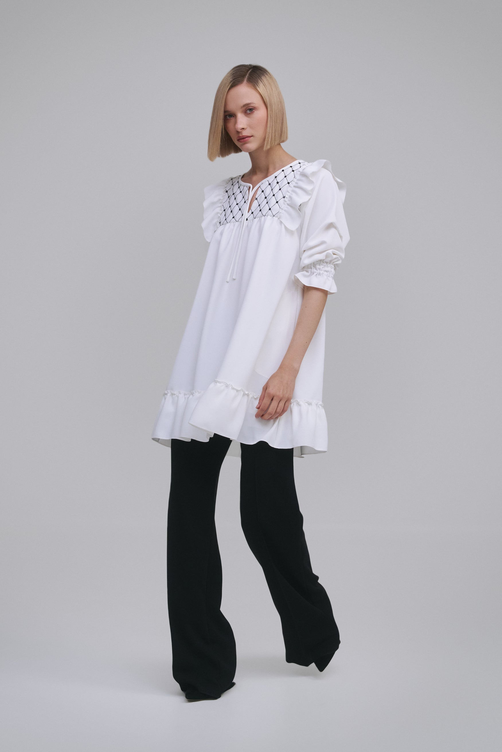 Model wears the Amelia Toro Embroidered Ruffled Short-Sleeve Mini Dress in White, front view