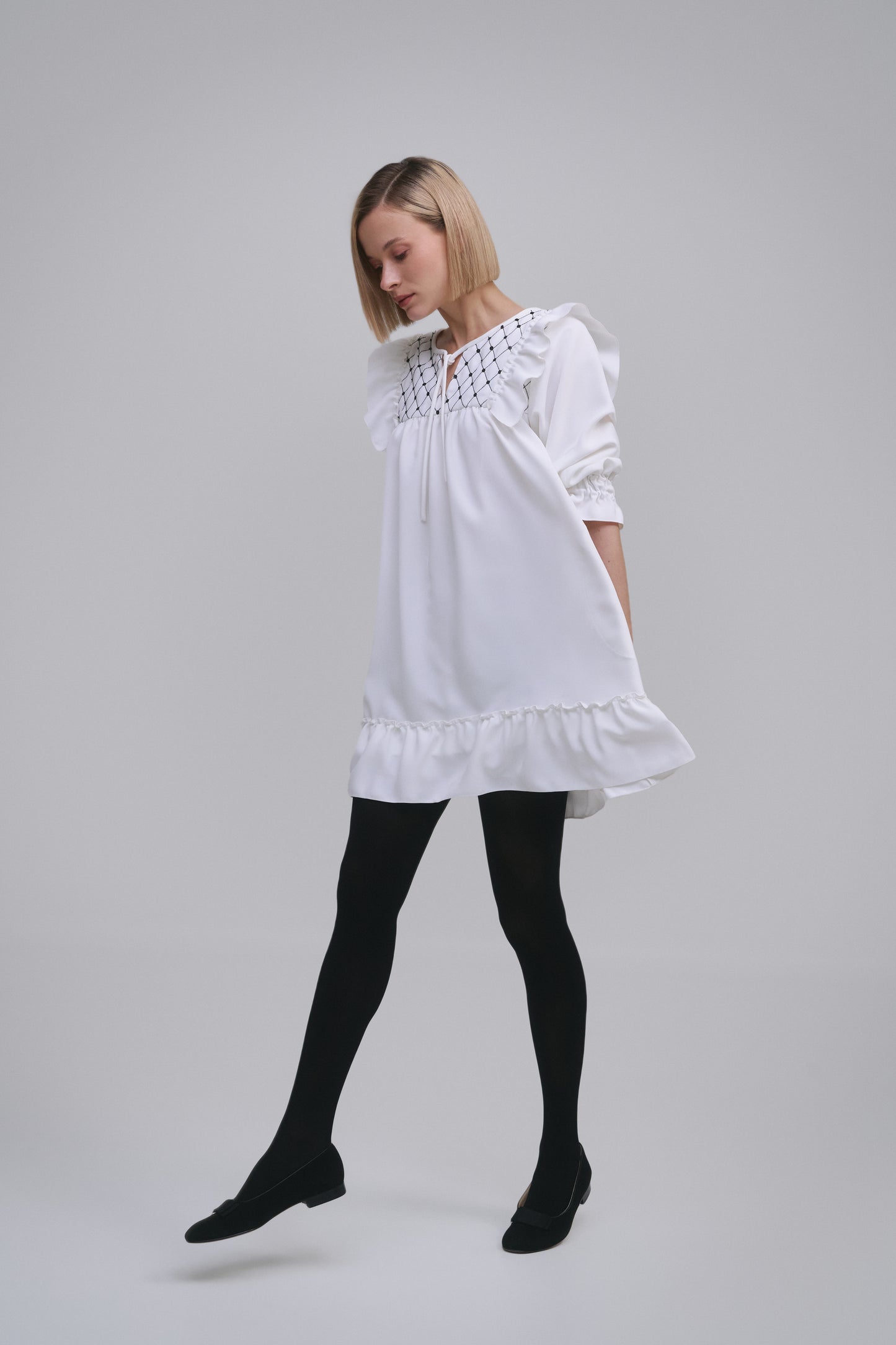 Model wears the Amelia Toro Embroidered Ruffled Short-Sleeve Mini Dress in White, front view