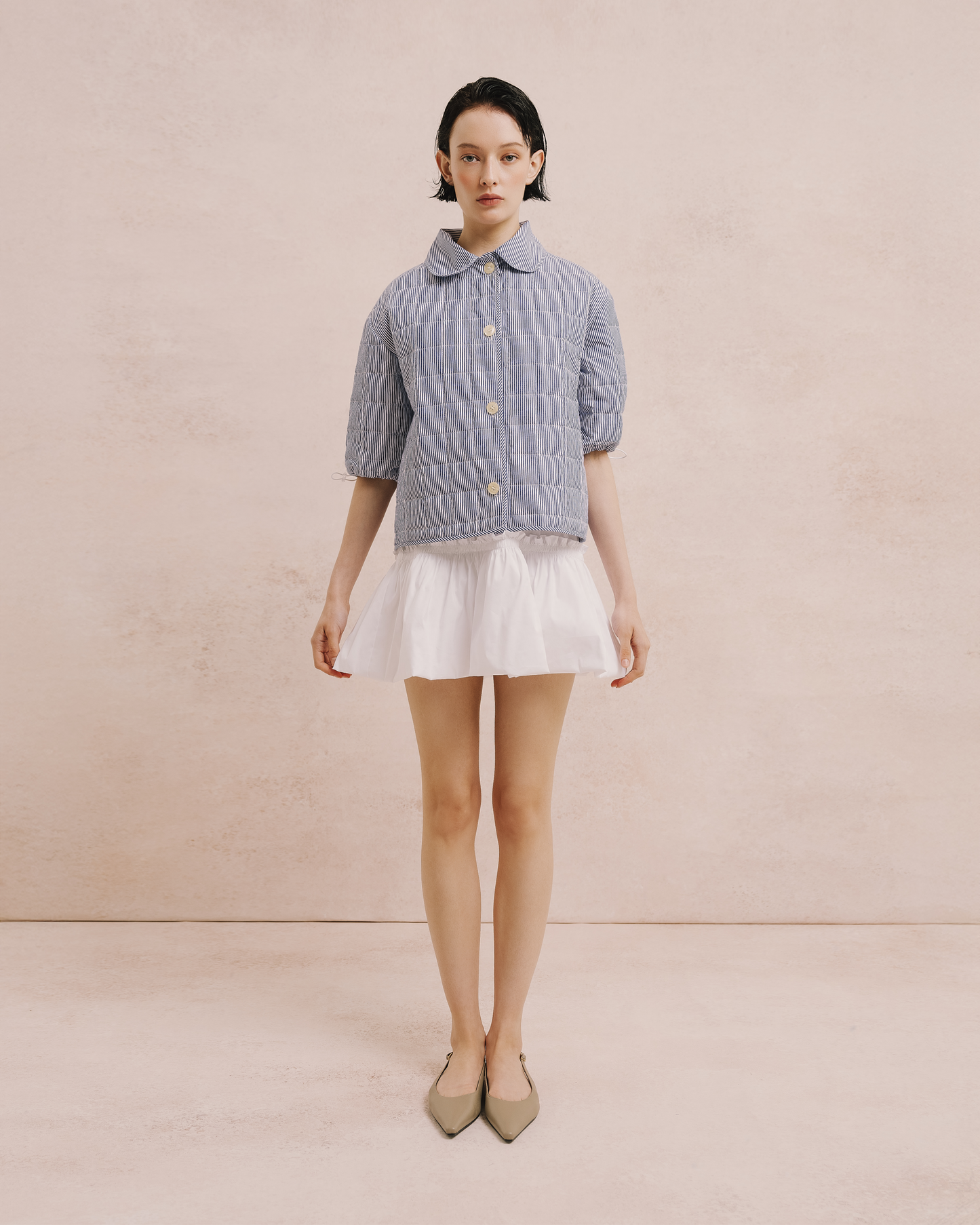 Model wears the Amelia Toro Gathered Bubble Mini Dress in white, front view