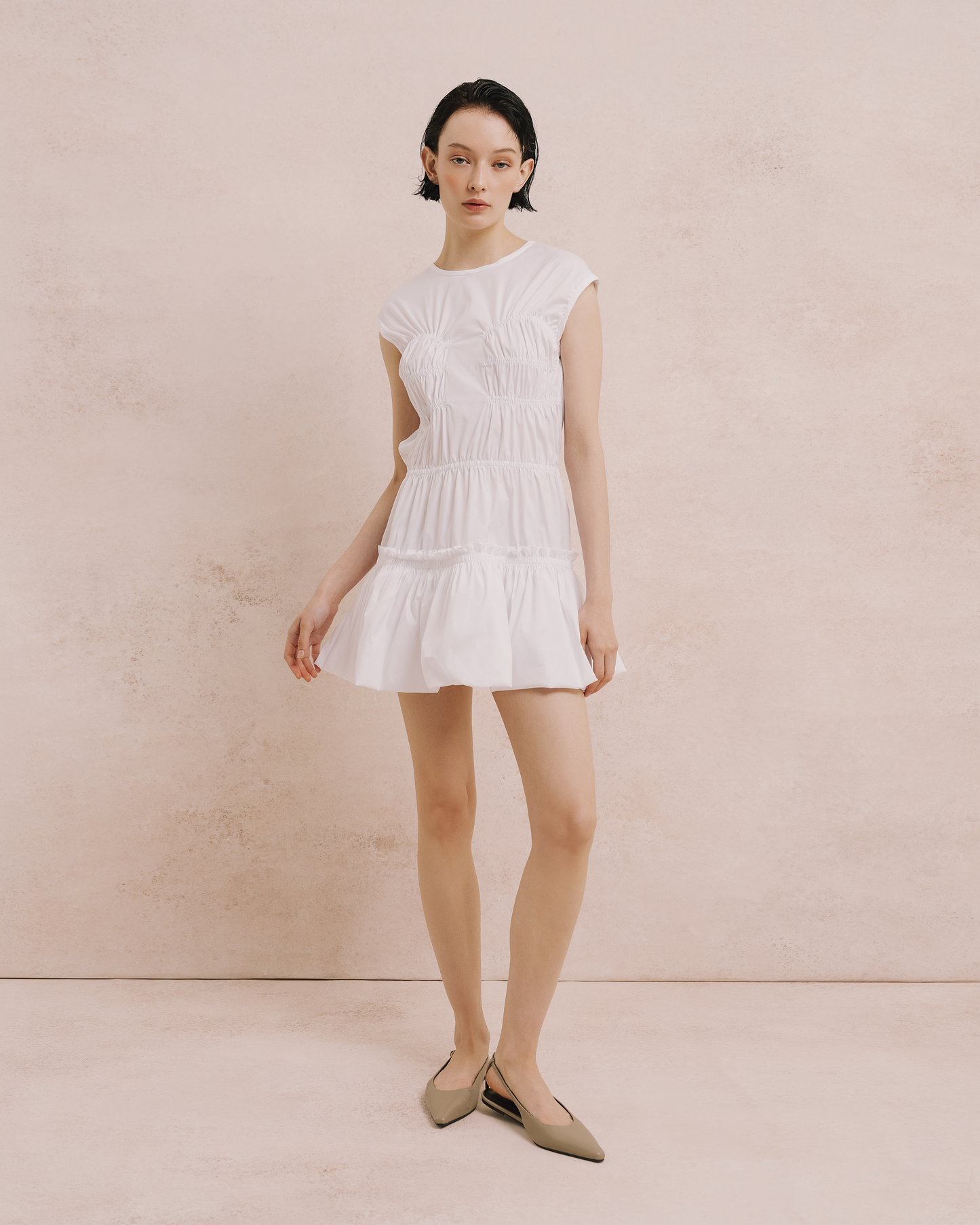 Model wears the Amelia Toro Gathered Bubble Mini Dress in white, front view