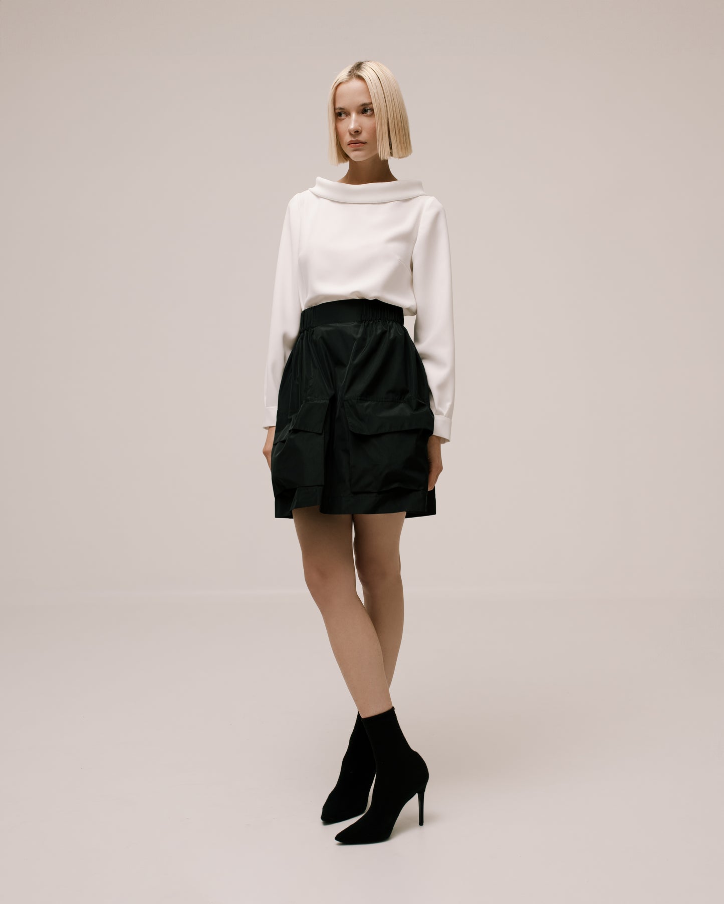 Model wears the Amelia Toro Gathered Taffeta Mini Skirt in Black, front view