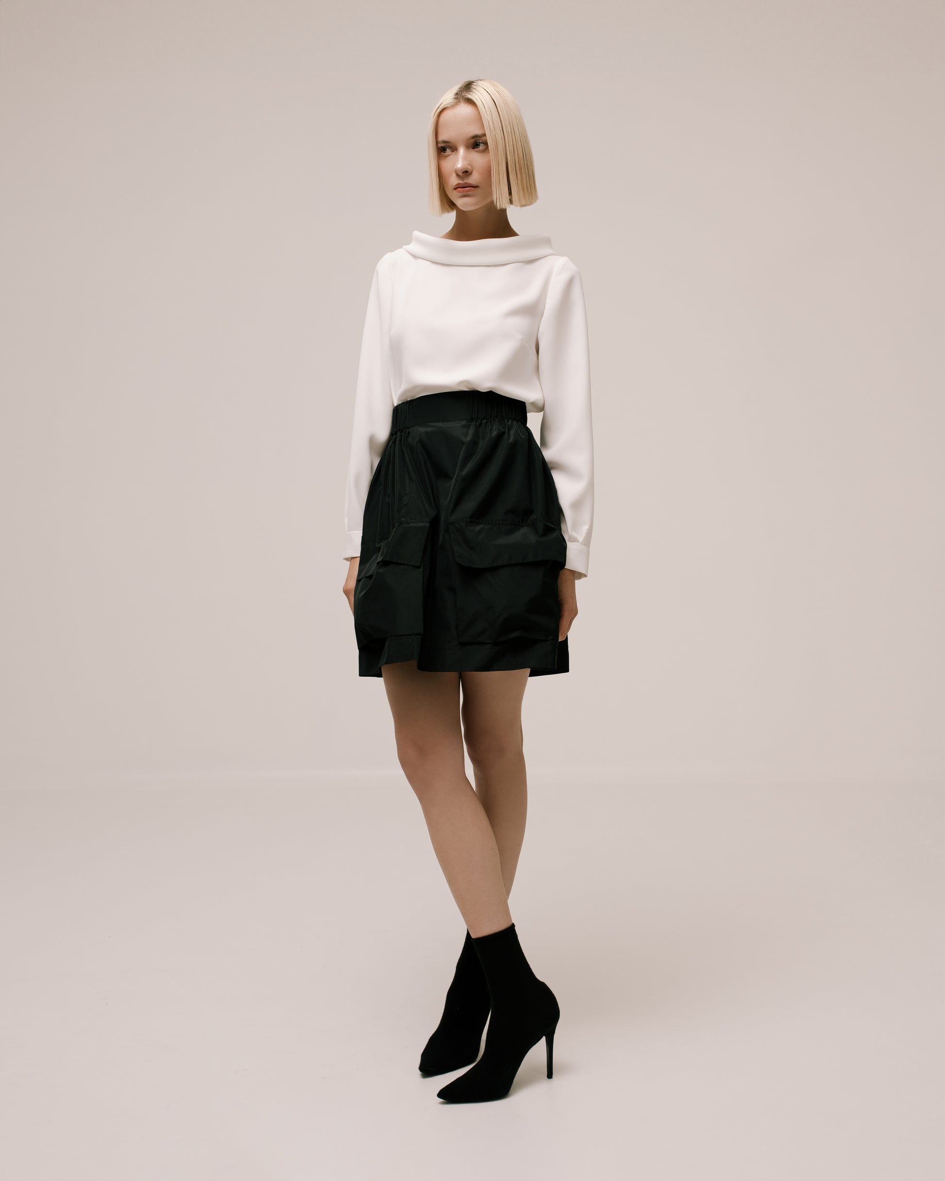 Model wears the Amelia Toro Gathered Taffeta Mini Skirt in Black, front view