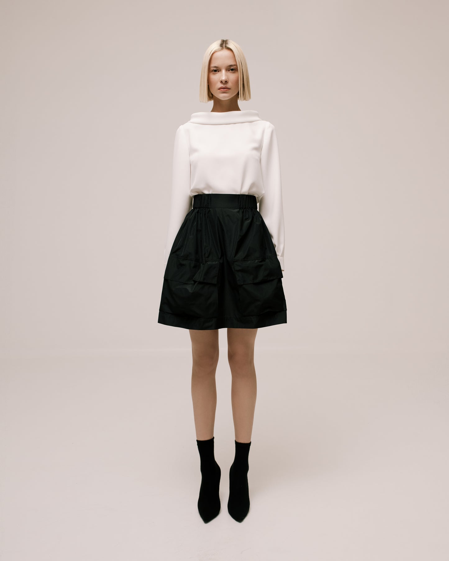 Model wears the Amelia Toro Gathered Taffeta Mini Skirt in Black, front view
