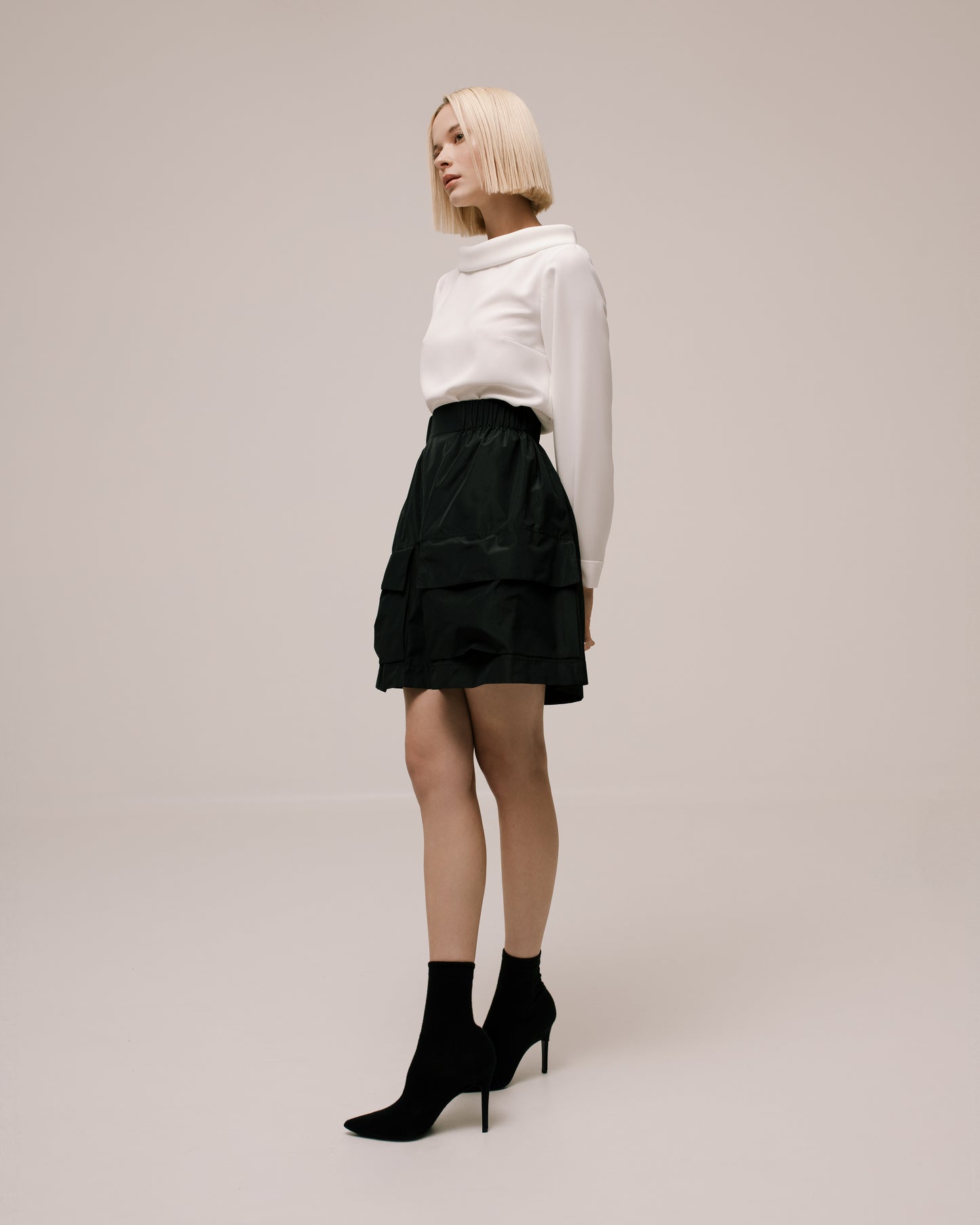 Model wears the Amelia Toro Gathered Taffeta Mini Skirt in Olive, front view