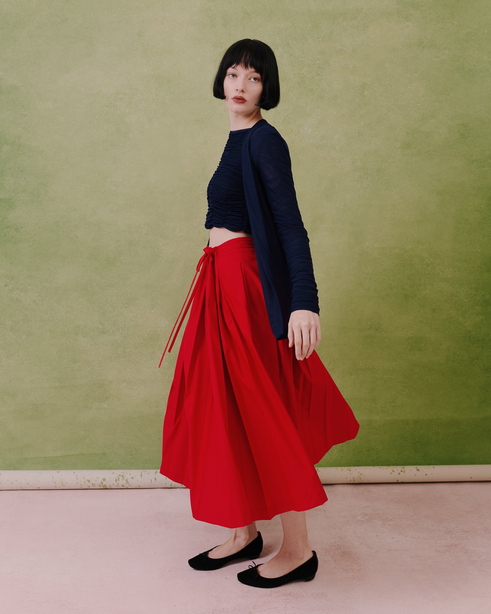 Model wears the Amelia Toro Gathered-Waist Pleated Midi Skirt in navy, front view