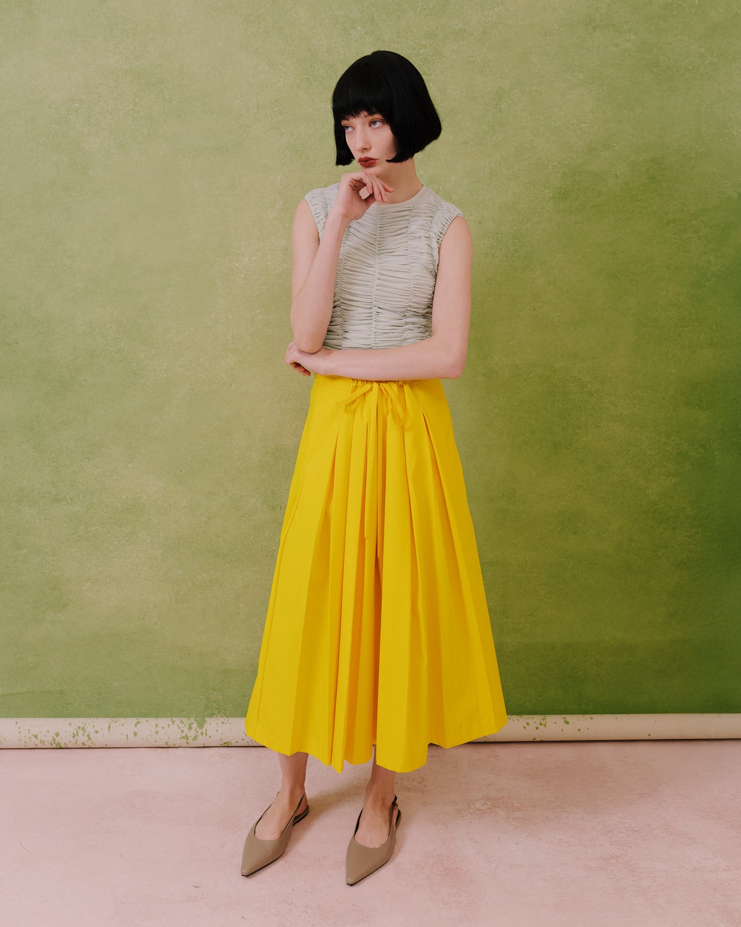Model wears the Amelia Toro Gathered-Waist Pleated Midi Skirt in yellow, front view