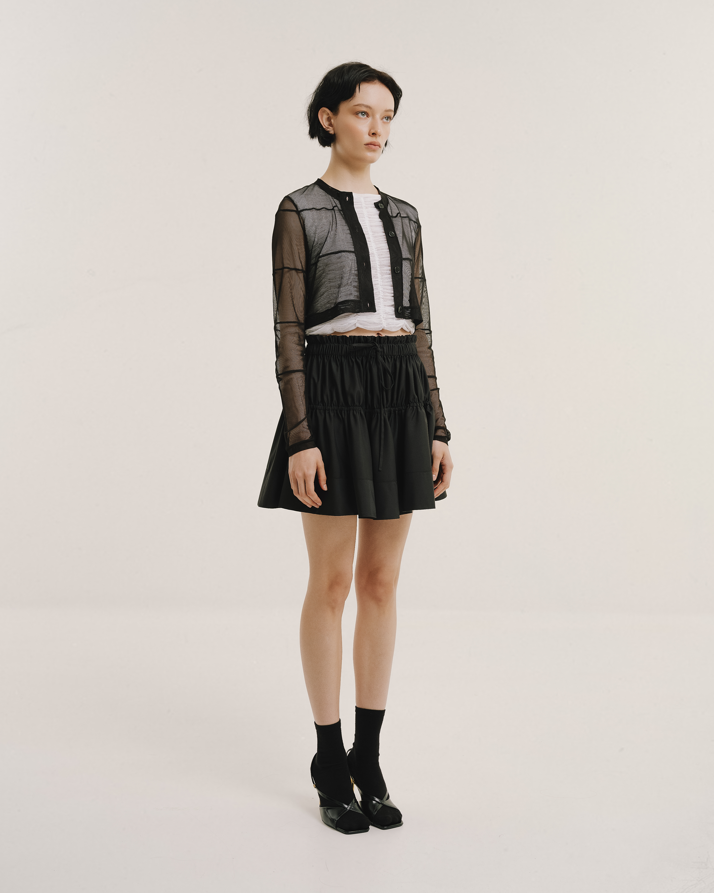 Model wears the Amelia Toro Gathered-Waist Pleated Mini Skirt in black, front view
