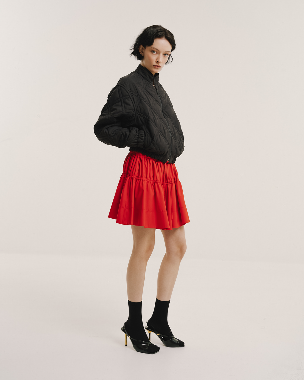 Model wears the Amelia Toro Gathered-Waist Pleated Mini Skirt in red, front view