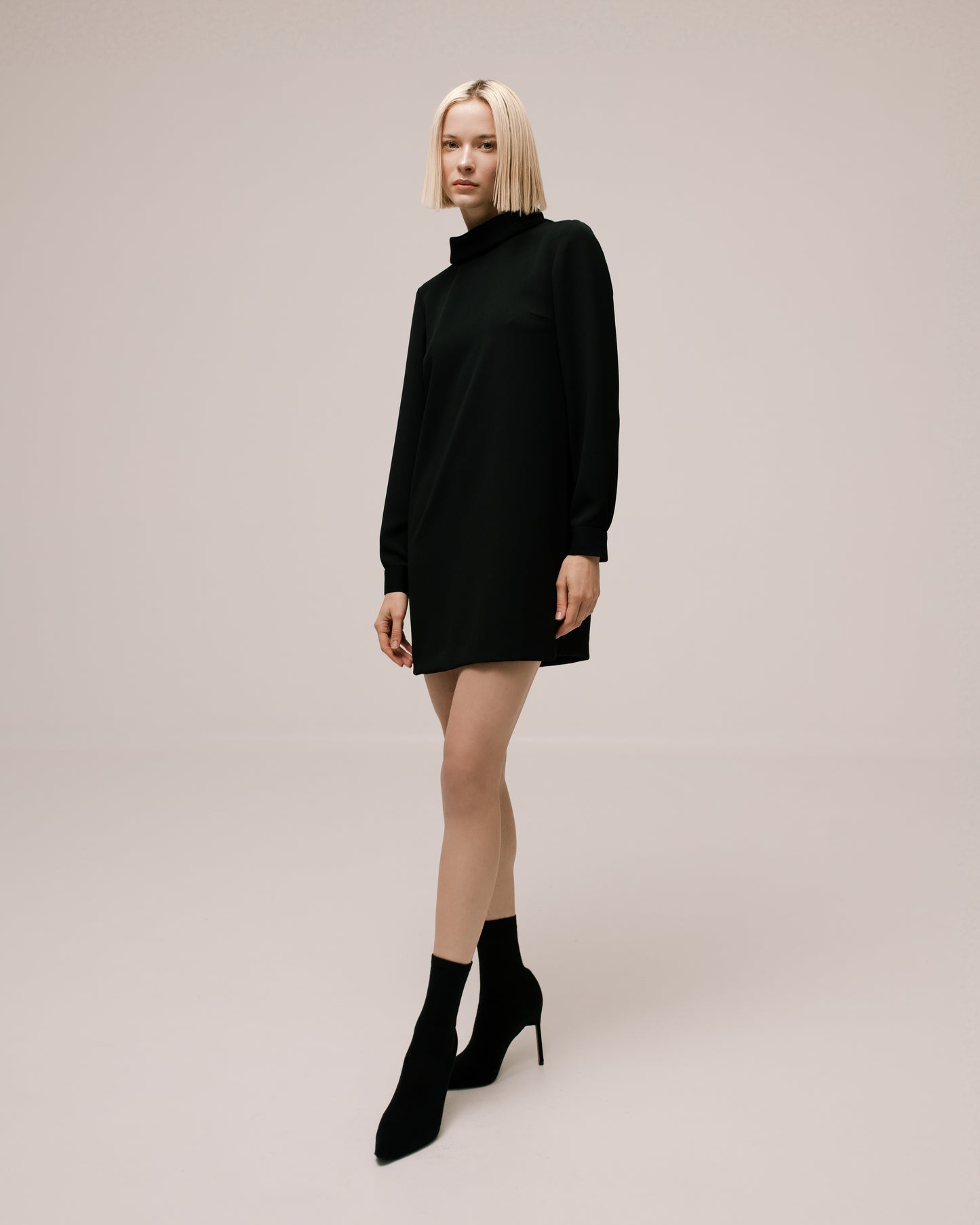 Model wears the Amelia Toro High-Neck Long-Sleeve Cady Mini Dress in Black, front view