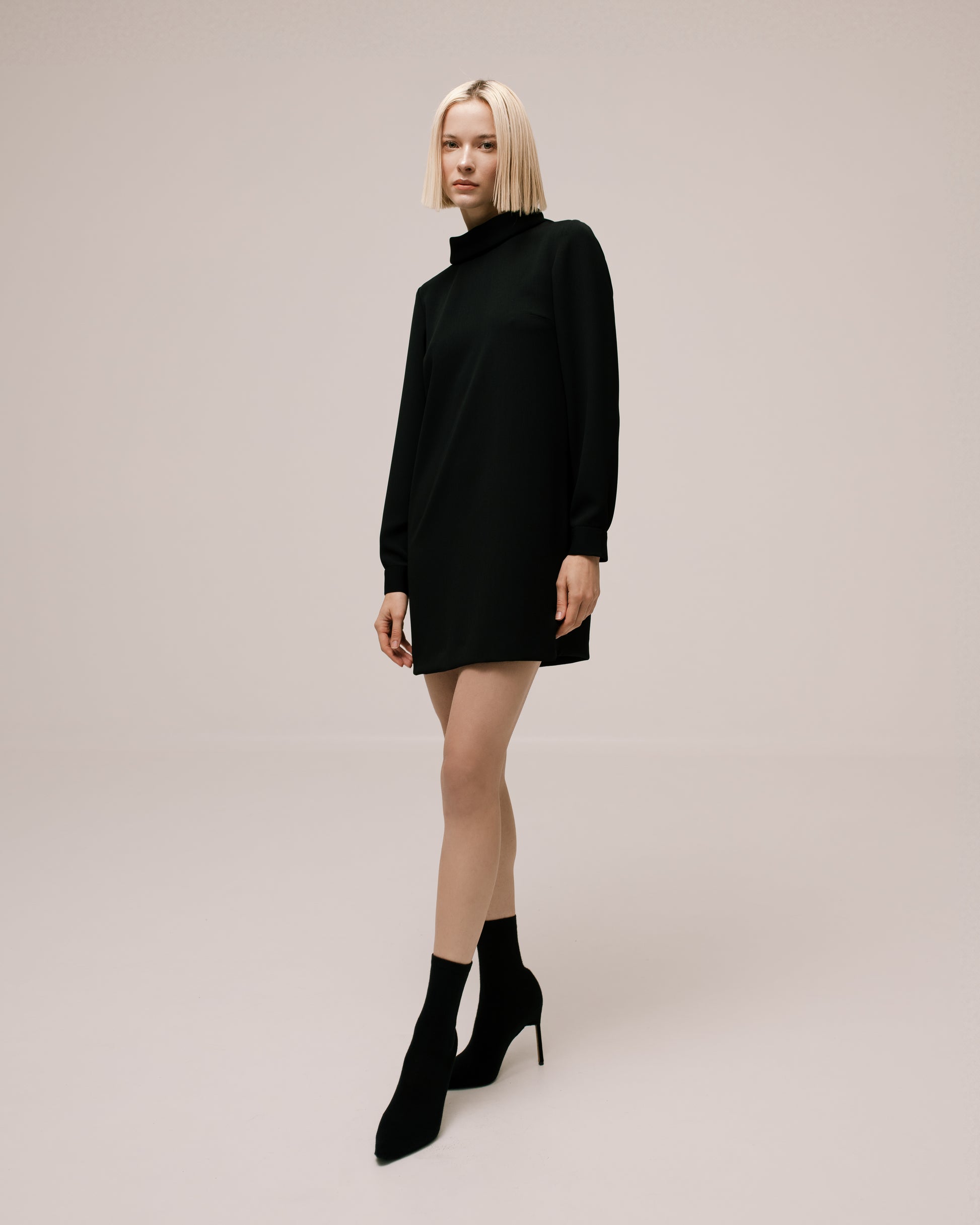 Model wears the Amelia Toro High-Neck Long-Sleeve Cady Mini Dress in Black, front view