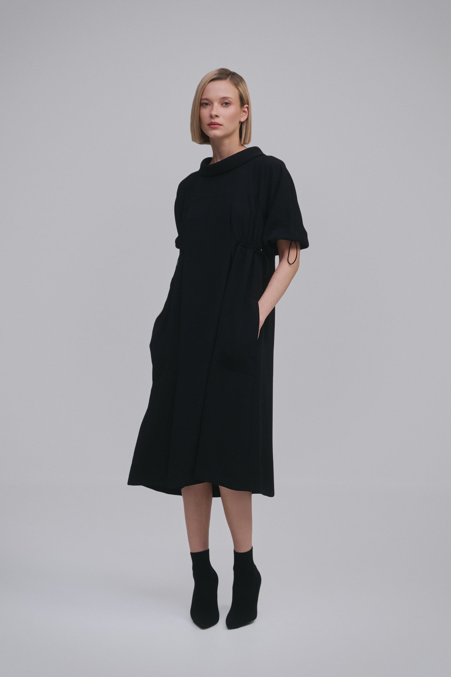 Model wears the Amelia Toro Loose Cowl-Neck Kimono-Sleeve Midi Dress in Black, front view