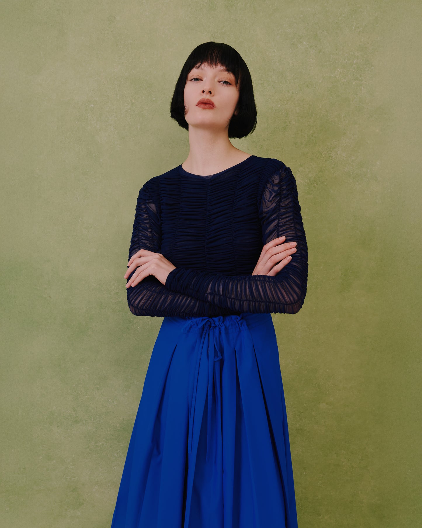 Close-up of the Amelia Toro ruched tulle long-sleeve crop top in navy, arms crossed