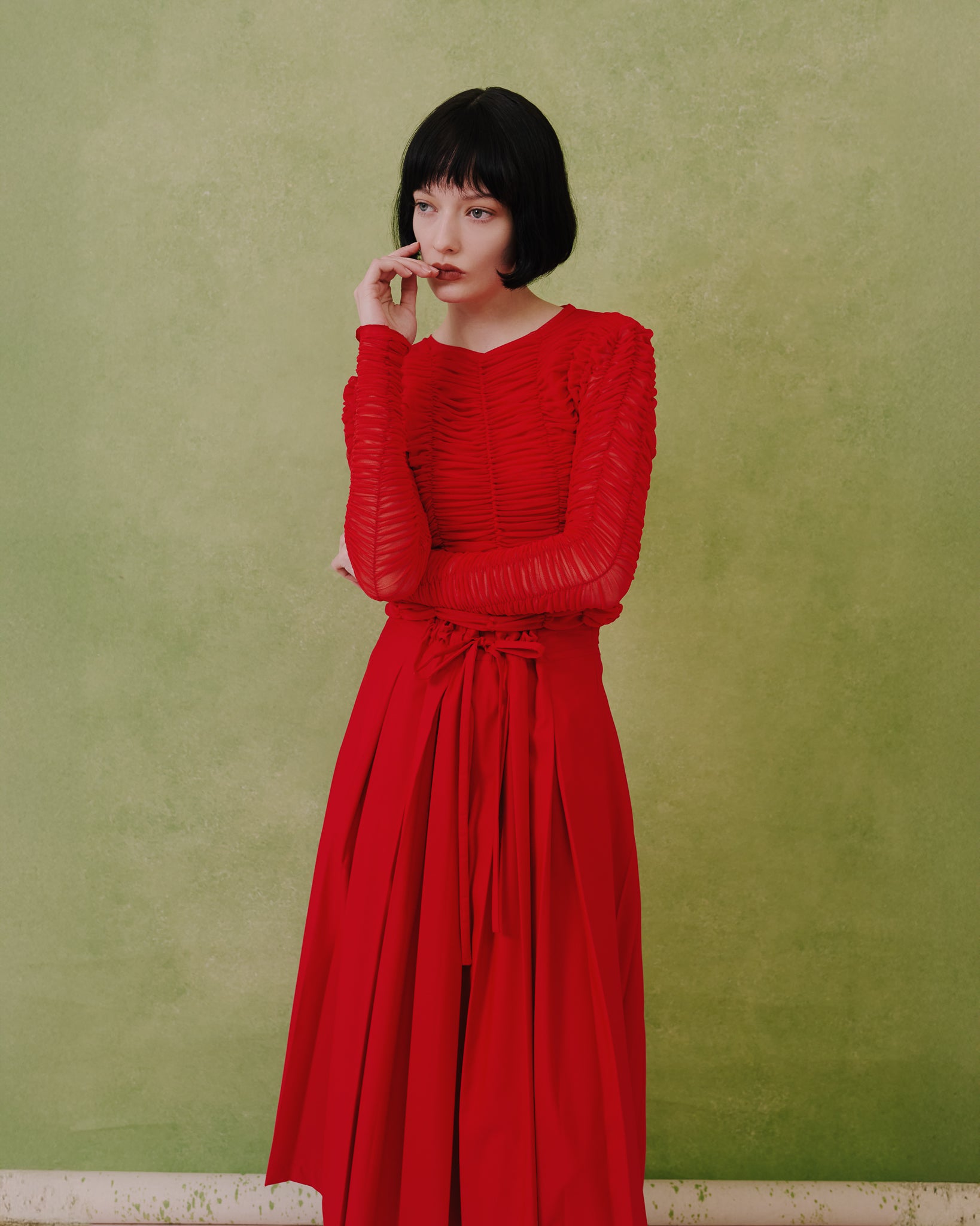 Model wears the Amelia Toro ruched tulle long-sleeve crop top in red, three-quarter view