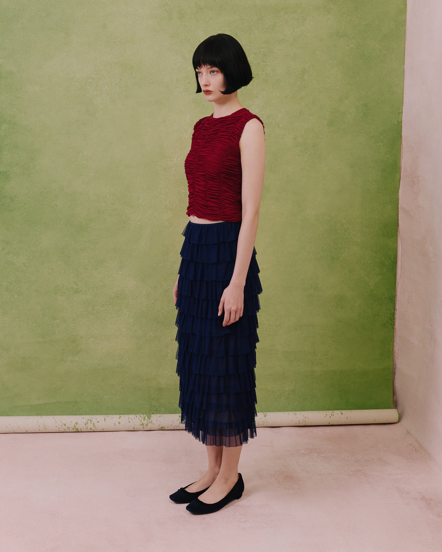 Model wears the Amelia Toro ruched tulle sleeveless top in plum, styled with a navy skirt