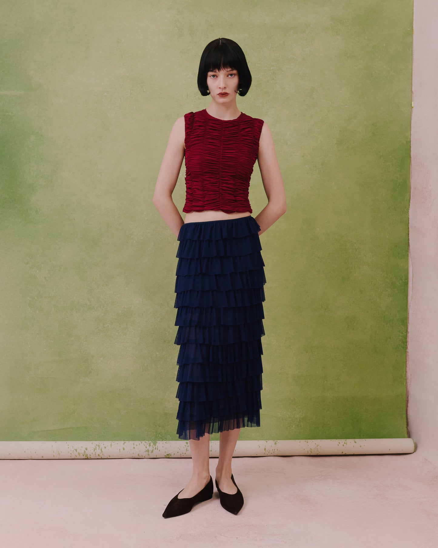Model wears the Amelia Toro ruched tulle sleeveless top in plum, styled with a navy skirt, front view