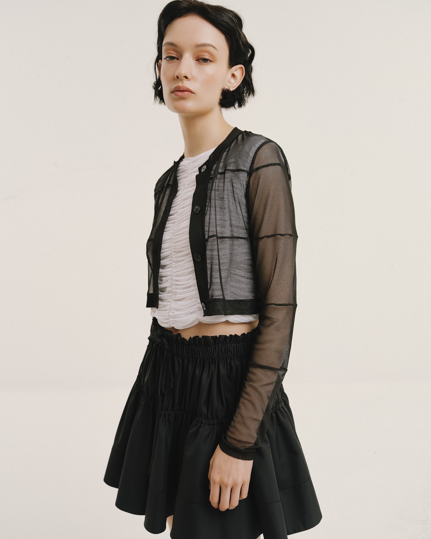 Amelia Toro ruched tulle sleeveless top in white, layered under a black sheer jacket