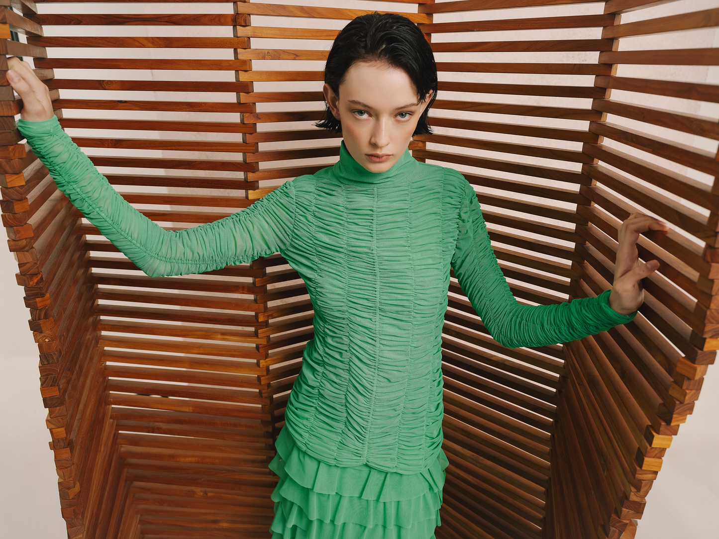 Model wears the Amelia Toro Ruched Tulle Turtleneck Top in green mint, styled with a green ruffled skirt, front view