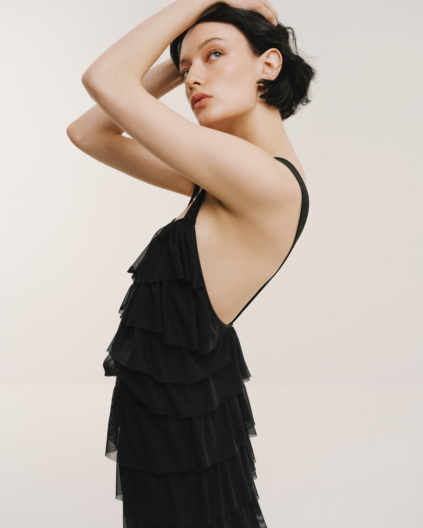 Model wears the Amelia Toro Ruffled Tulle Evening Gown in black, front view
