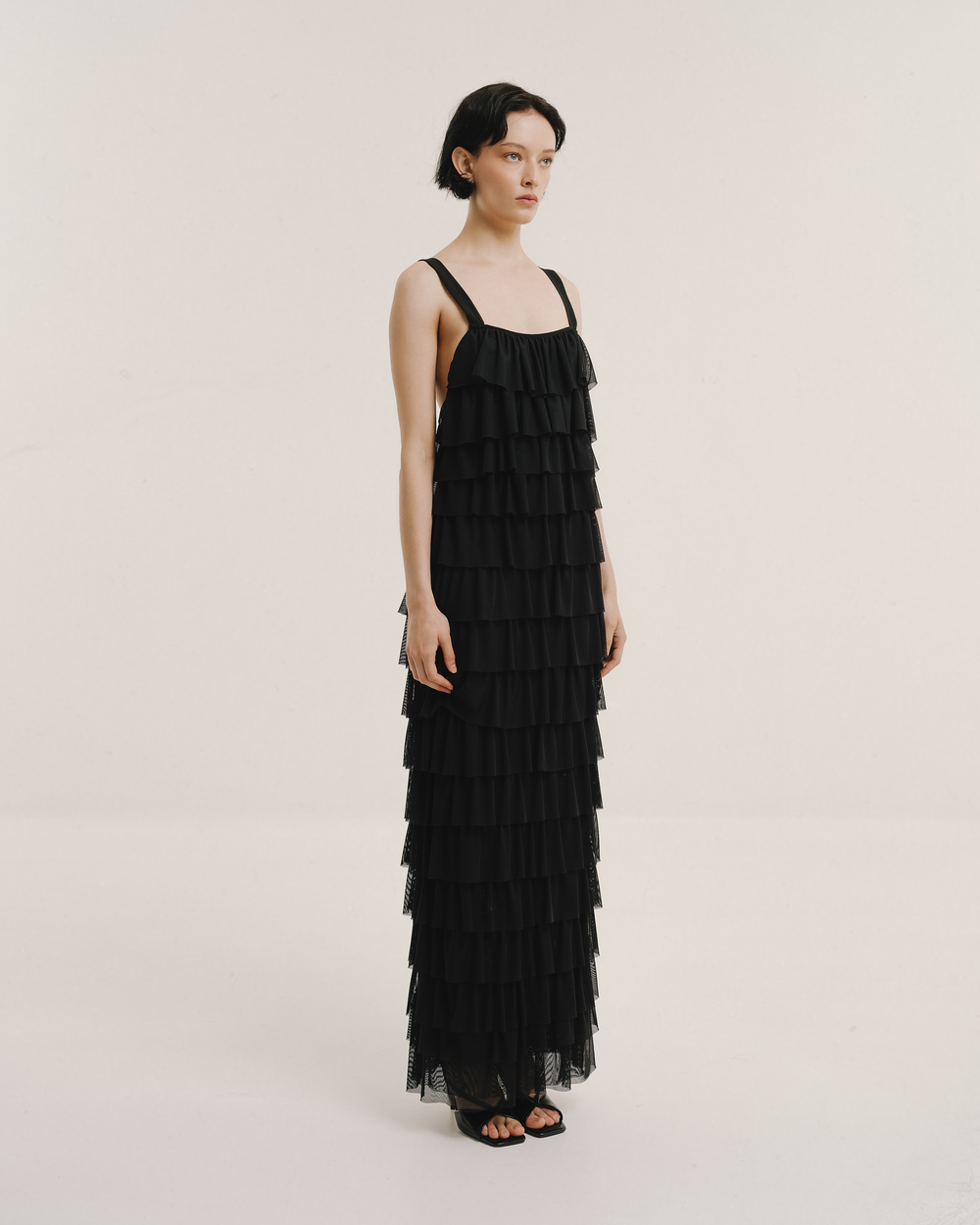 Model wears the Amelia Toro Ruffled Tulle Evening Gown in black, front view