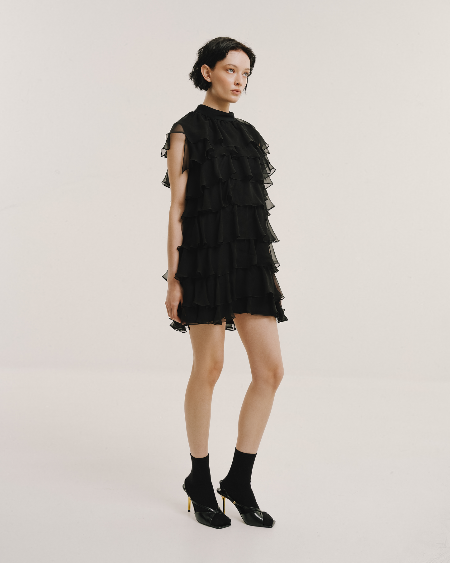 Model wears the Amelia Toro Silk Chiffon Tiered Ruffle Mini Dress in black, front view
