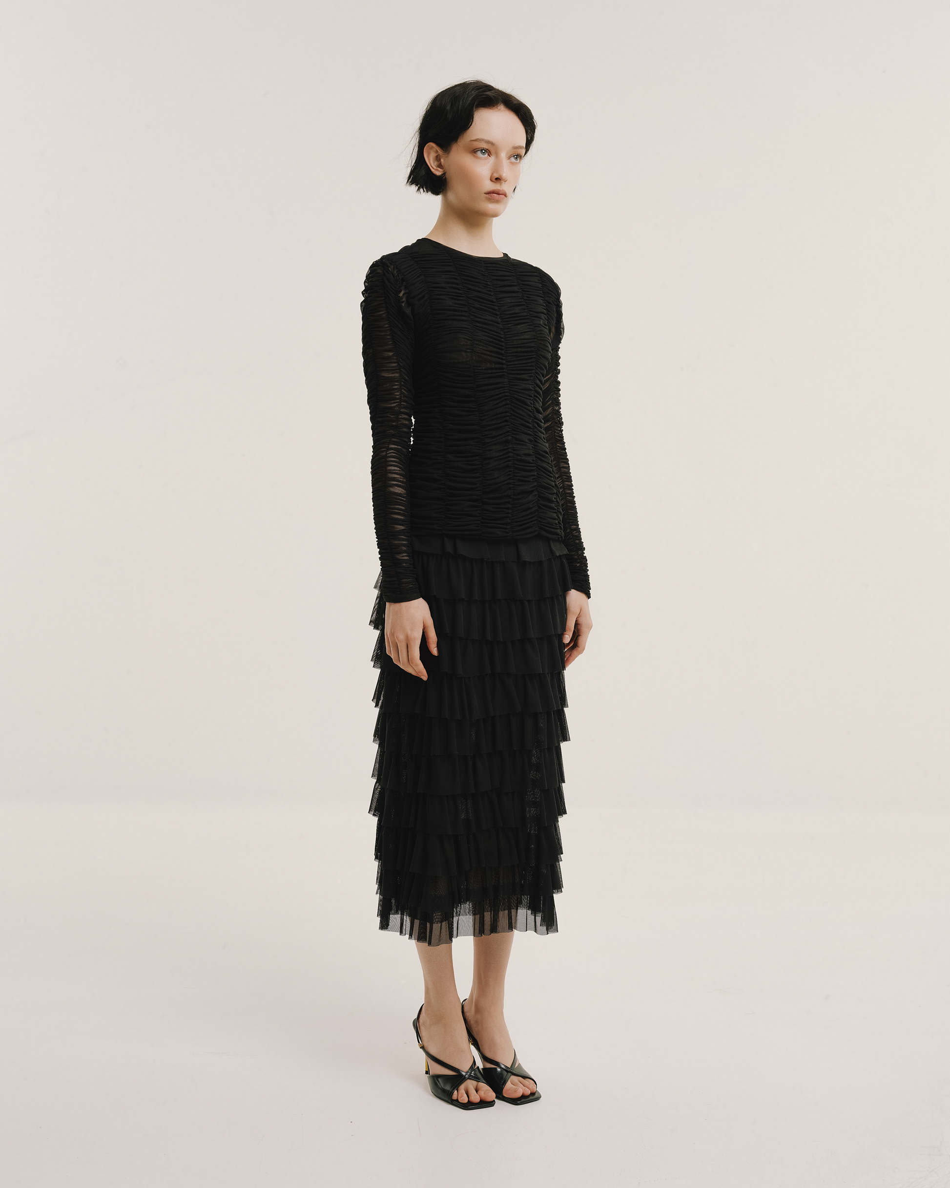 Model wears the Amelia Toro Tiered Ruffle Tulle Maxi Skirt in black, front view