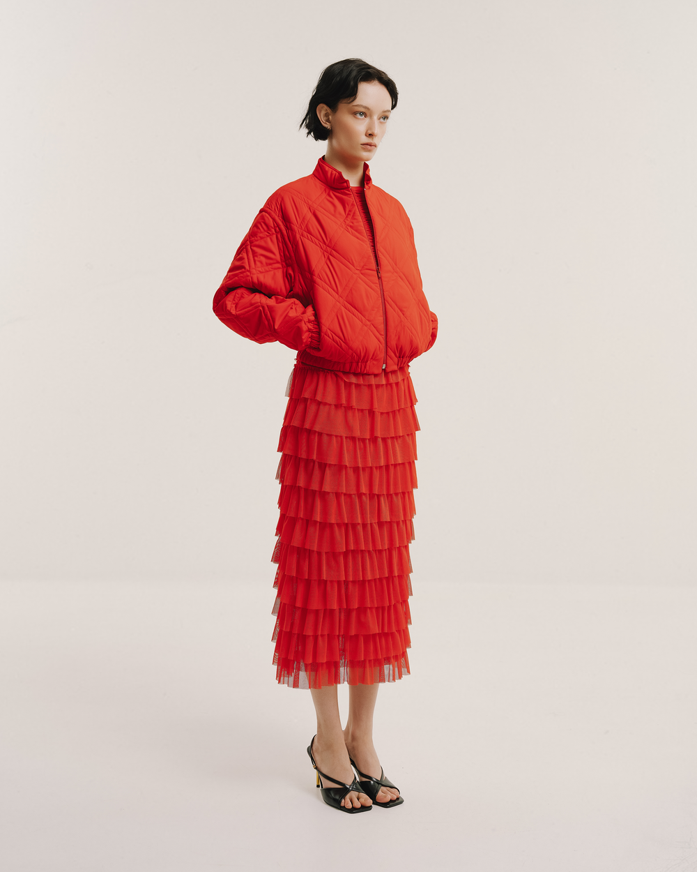 Model wears the Amelia Toro Tiered Ruffle Tulle Maxi Skirt in red, front view