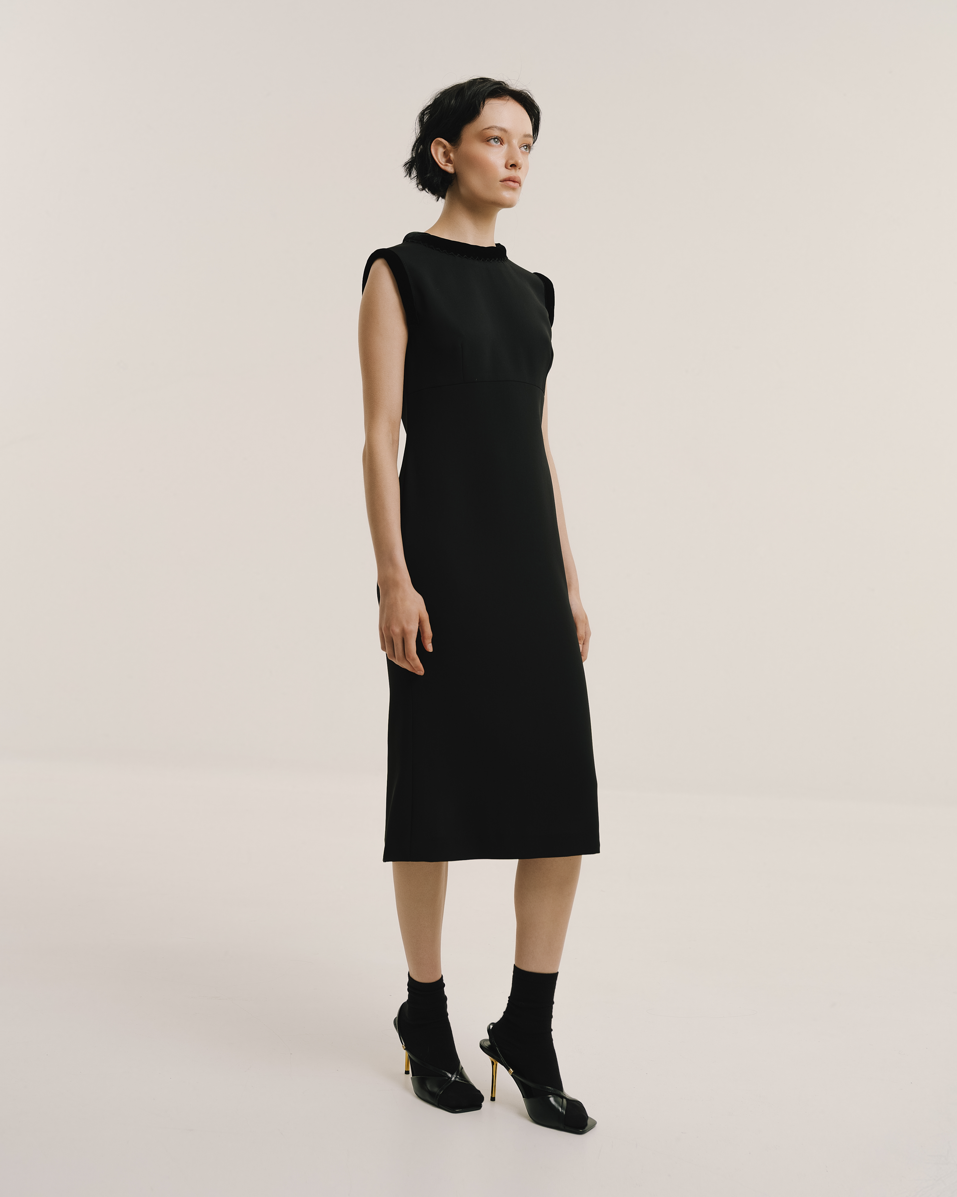 Model wears the Amelia Toro Velvet-Trimmed Black Midi Dress in black, front view