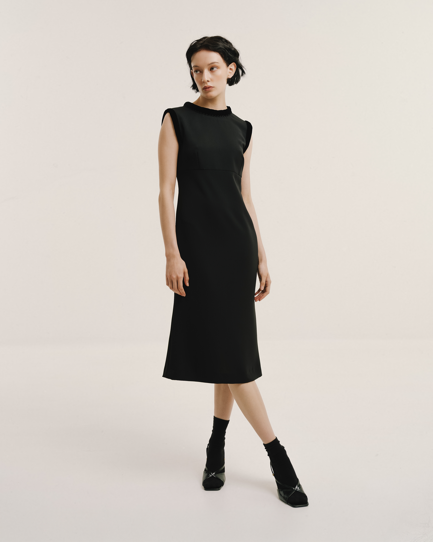 Model wears the Amelia Toro Velvet-Trimmed Black Midi Dress in black, front view